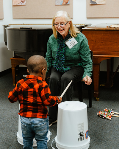 Faculty member Juanita Clendaniel with a young visitor at the Milford Branch exploring percussion