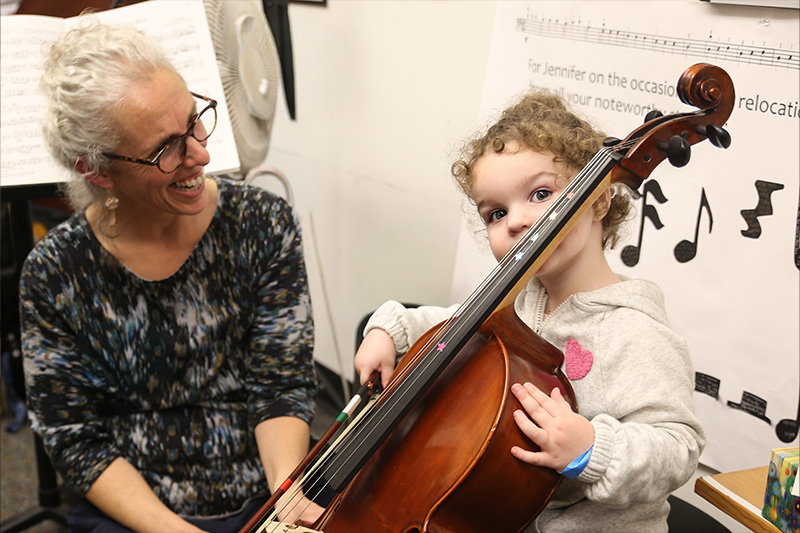 A young visitor tries a cello with Cello faculty member Banu Fields
